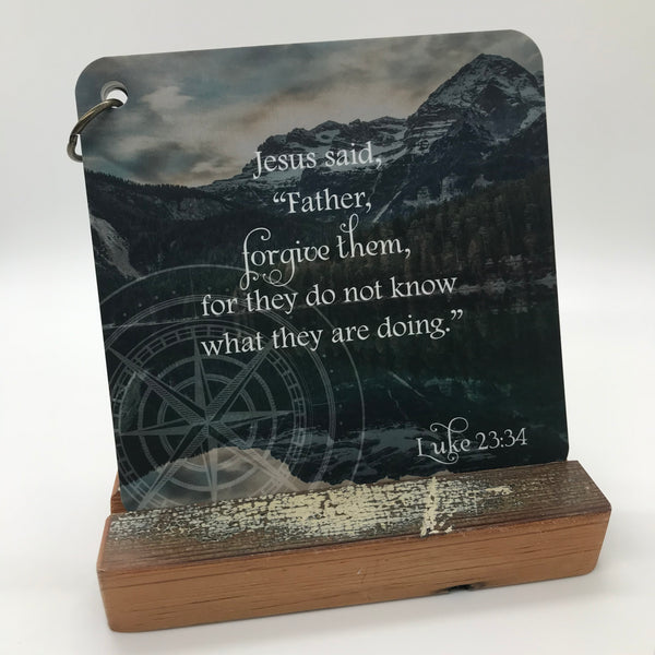 Scripture card with Luke 23:34 printed over a photo of mountains and an angry looking sky. Bible verse for the day.