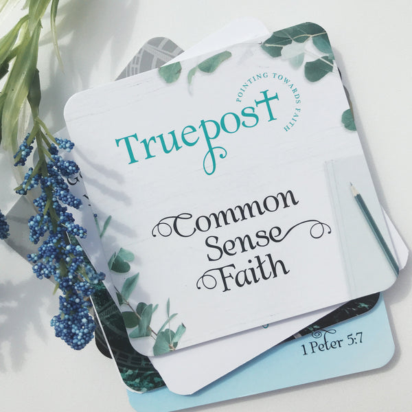 Photo of mini scripture cards called Common Sense Faith with the cover card on top and the cards with bible verses are stacked on top of each other under the cover card. There is a blue flower laying beside them.  They are laying on a white background.
