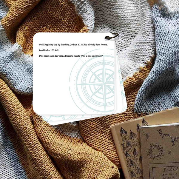 Devotion card on thanking God laying on a brown and blue blanket.