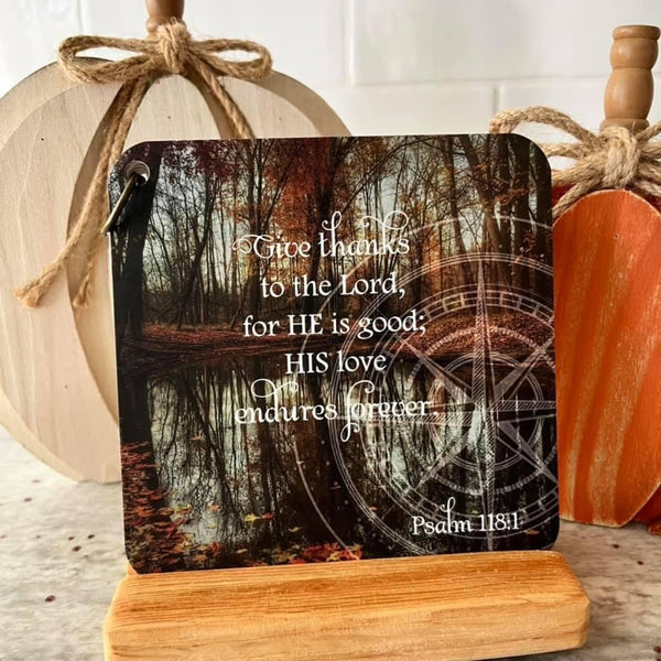 Give thanks scripture card on a wooden easel with pumpkins in the background. Scripture of Psalm 118:1