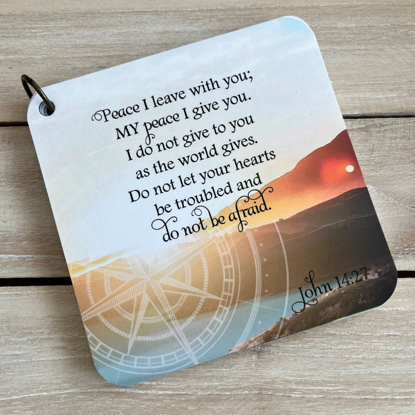 A scripture devotional card with John 14:27 printed over a photpgraph of a sunset over the mountains. There is a compass rose etched in the background.