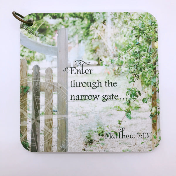 Scripture card of Matthew 7:13 printed over a photo of a white gate with vines growing around it.