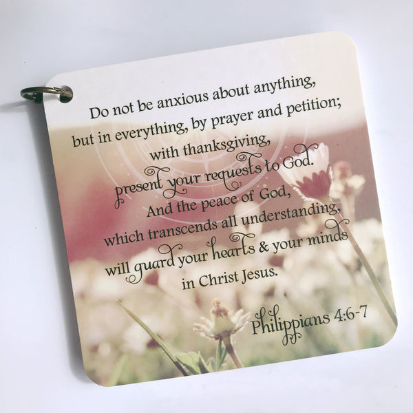 Scripture card on anxiety from Philippians 4:6-7 printed over a photo of flowers in a field. Daily scripture card.