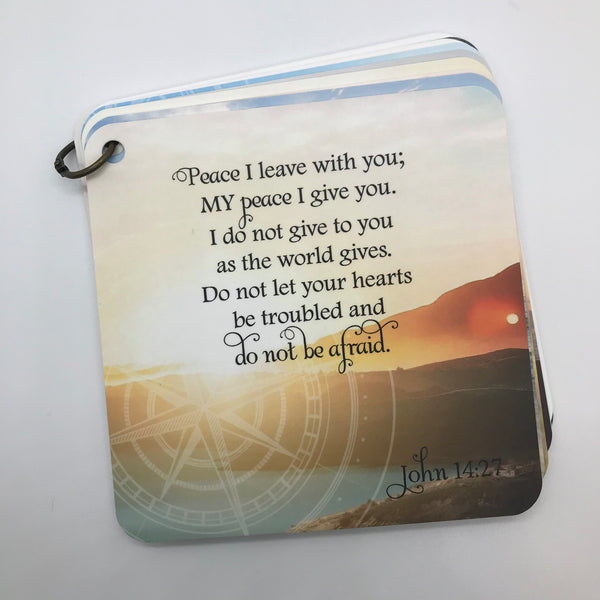 Scripture card with John 14:27 printed over a photo of a sun setting over a few small mountains and a small body of water. Daily scripture card.