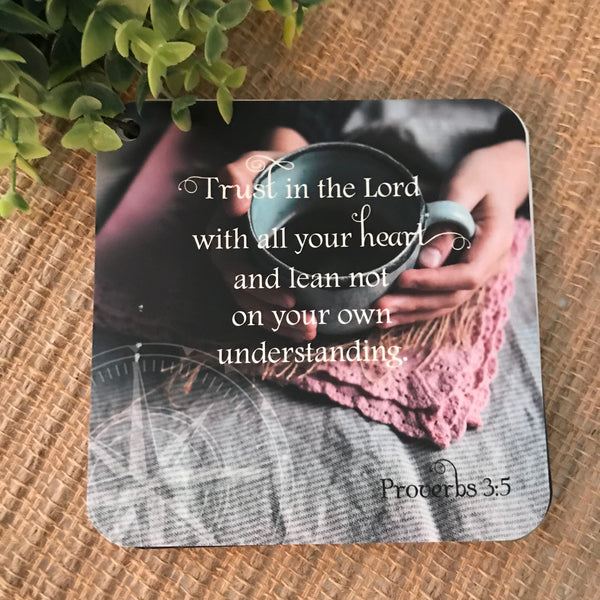 Scripture card of Proverbs 3:5 trust in the Lord with all your heart and lean not on your own understanding printed over a photo of hands holding coffee. Daily Bible verse card.