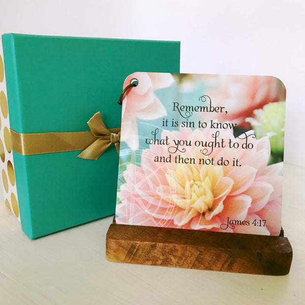 Gift box with white bottom with gold metalic dots on it. The cover to the box is turquoise with a gold metalic bow. Next to the box is a scripture devotional card displayed on a walnut wood easel. The card has James 4:17 printed over a photo of blooming peach colored flowers. 