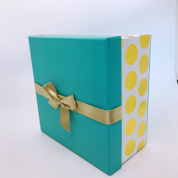 The gift box. It's bottom is a white background with metalic gold dots all over it. The cover is turquoise with a gold metalic bow. 