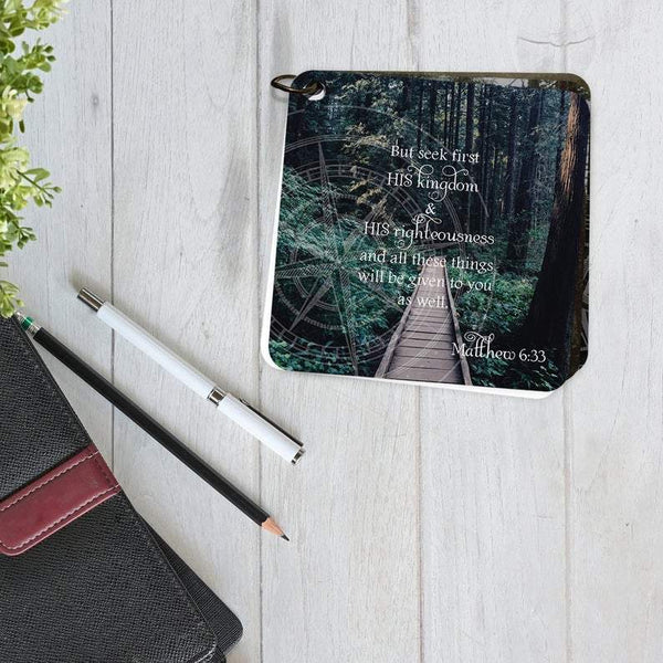 Scripture card of Matthew 6:33 is printed over a photo of a small, narrow, wooden bridge through a lush green forest. 