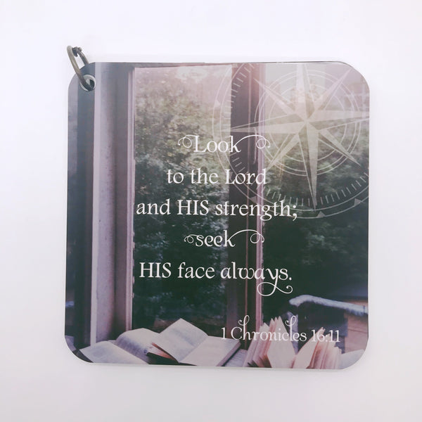 Scripture card for 1 Chronicles 16:11 printed over a photo of books in a window looking out over trees.