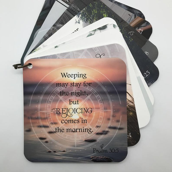 Scripture card of Psalm 30:5 weeping may stay for the night but rejoicing comes in the morning printed over a photo of a sunset on the beach, fanned out with the other cards behind it.