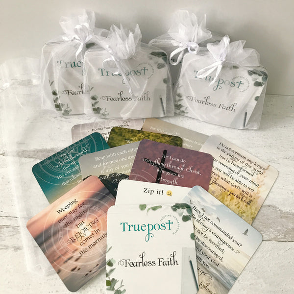 Ten mini scripture cards fanned out with four sets in white organza bags in the background.